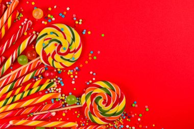 Kırmızı arka planda renkli şekerler. Lolipop. Üst te. Kopya 
