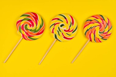 Sarı bir arka plan üzerinde renkli şeker. Lolipop. Üst te. Kopya