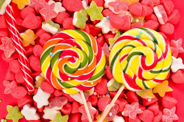 Assorted colorful gummy candies and lollipop on red background. — Stock Photo, Image