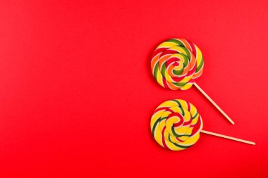 Kırmızı arka planda renkli şekerler. Lolipop. Üst te. Kopya sp