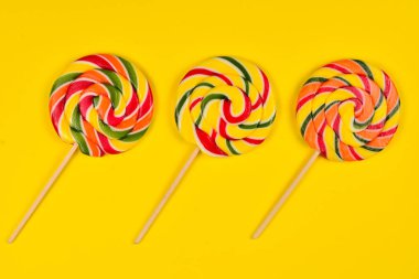 Sarı bir arka plan üzerinde renkli şeker. Lolipop. Üst te. Kopya