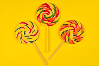 Sarı bir arka plan üzerinde renkli şeker. Lolipop. Üst te. Kopya