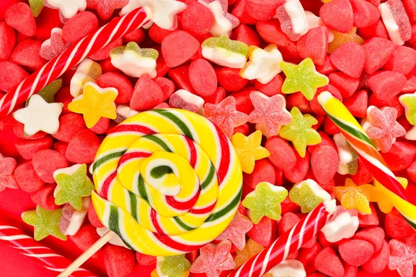 Разнообразные красочные конфеты и леденец на красном фоне . — стоковое фото