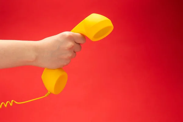 女性の手に赤い背景に黄色の携帯電話 スペースのコピー — ストック写真