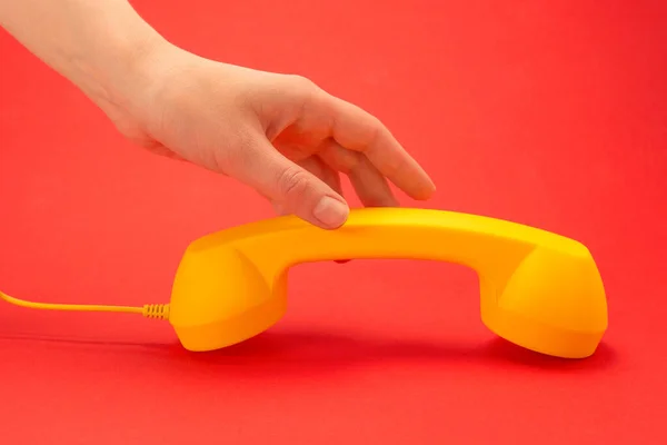 Gele Handset Een Rode Achtergrond Vrouwenhand Kopieerruimte — Stockfoto