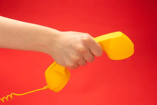 Żółty Telefon Czerwonym Tle Dłoni Kobiety Przestrzeń Kopiowania — Zdjęcie stockowe