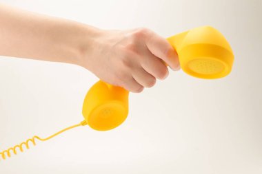 Kadının elindeki sarı cep telefonu beyaza izole edilmiş. Boşluğu kopyala.