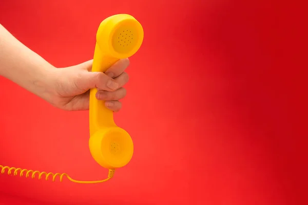 Gele Handset Een Rode Achtergrond Vrouwenhand Kopieerruimte — Stockfoto