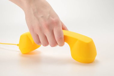 Kadının elindeki sarı cep telefonu beyaza izole edilmiş. Boşluğu kopyala.