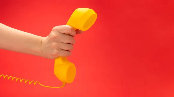 Żółty Telefon Czerwonym Tle Dłoni Kobiety Przestrzeń Kopiowania — Zdjęcie stockowe