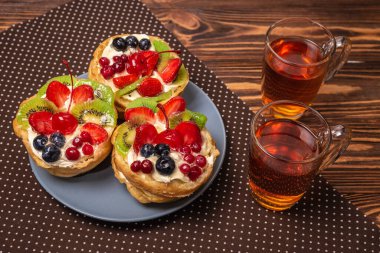 Kremalı ve meyveli ev yapımı pasta ve ahşap zemin üzerinde sıcak çay.. 