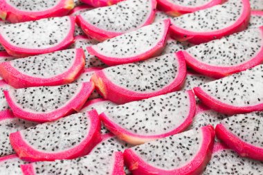 Tatlı ejderha meyvesi ya da pitaya dilimleri arka planda.