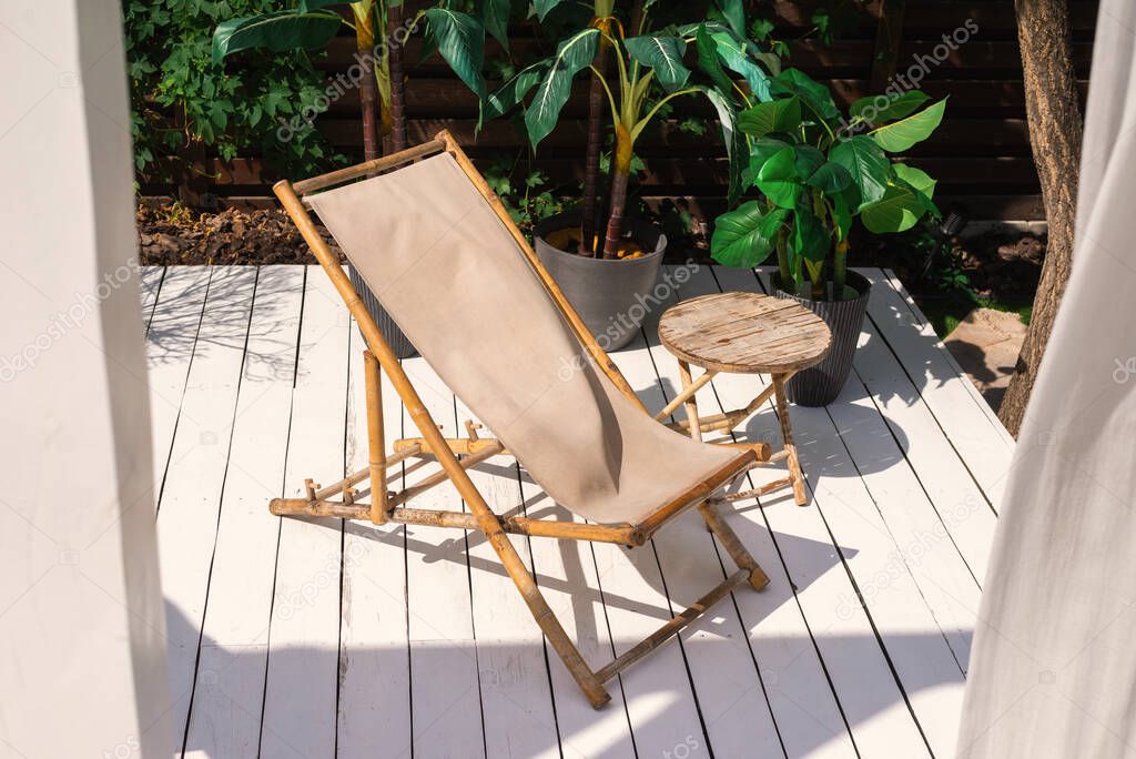 Comfortable bamboo chair and table, plants outdoor. Comfort zone.