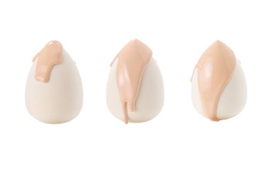 Beyaz arka planda izole edilmiş yeni beyaz süngerin üzerine dökülen sıvı bej makyaj vakfı