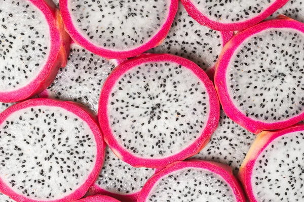Tatlı ejderha meyvesi ya da pitaya dilimleri arka planda.