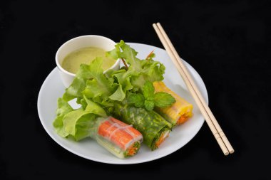 Plaka, salata rulo, siyah zemin üzerinde soslu taze sebze şehriye böreği. Diyet ya da aşçı kavramı.