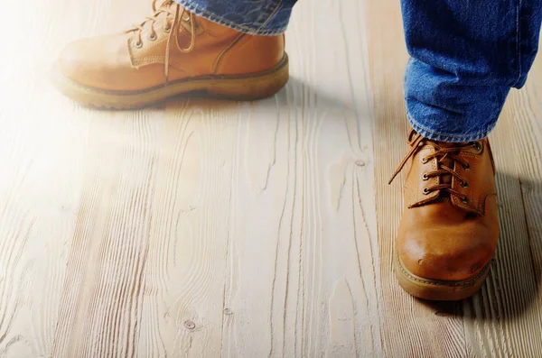 Carpenter feet in work boots standing on wooden floor. Place for text ...