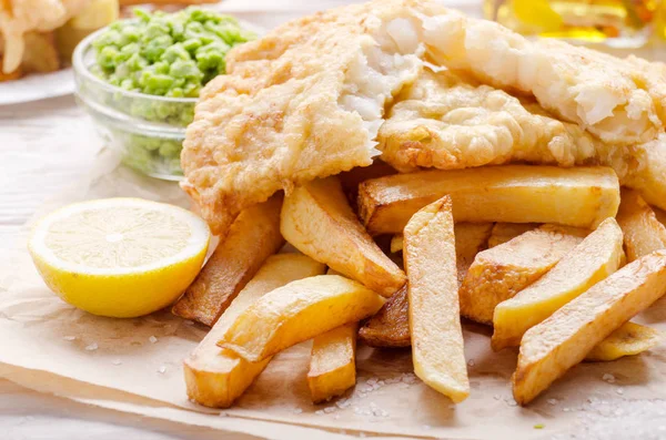 Traditional British street food fish and chips with mushy peas on parchment paper