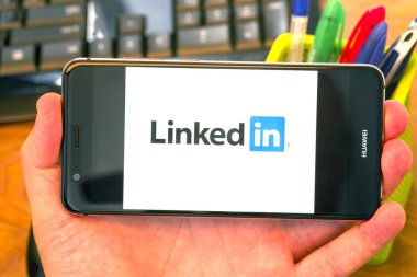 Piatra Neamt, Romanya - 30 Temmuz 2018: El bir cep telefonu ile LinkedIn logo üstünde belgili tanımlık perde, office arka plan tutar.