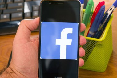 Piatra Neamt, Romanya - 30 Temmuz 2018: El bir cep telefonu ile Facebook logo üstünde belgili tanımlık perde, office arka plan tutar..
