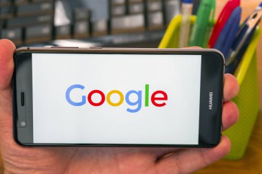 Piatra Neamt, Romanya - 30 Temmuz 2018: Google cep telefonuyla ekranında, office arka plan el tutar.