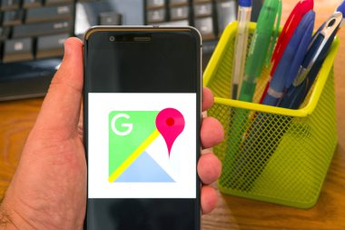 Piatra Neamt, Romanya - 30 Temmuz 2018: Bir cep telefonu ile Google logo üstünde perde, office arka plan haritalar el tutar.