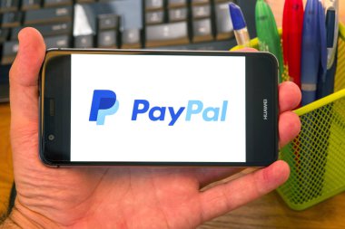 Piatra Neamt, Romanya - 30 Temmuz 2018: Paypal ile bir cep telefonu ekranında, office arka plan el tutar.