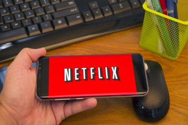 Piatra Neamt, Romanya - 30 Temmuz 2018: El Samsung S8 + Netflix ile tutan üstünde belgili tanımlık perde, office arka plan.