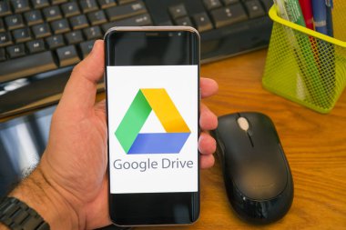 Piatra Neamt, Romanya - 30 Temmuz 2018: El Samsung S8 + Google sürücü logosu ile tutan üstünde belgili tanımlık perde, office arka plan.