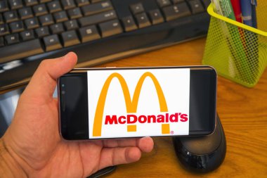 Piatra Neamt, Romanya - 30 Temmuz 2018: El Samsung S8 + Mcdonald's logolu tutan üstünde belgili tanımlık perde, office arka plan.
