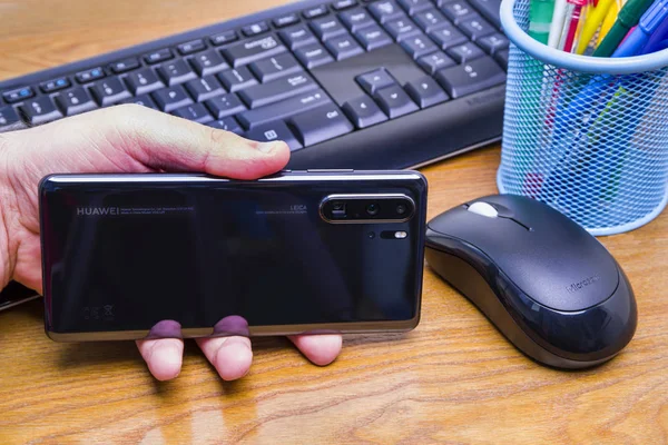 Mão com a nova Huawei no escritório — Fotografia de Stock