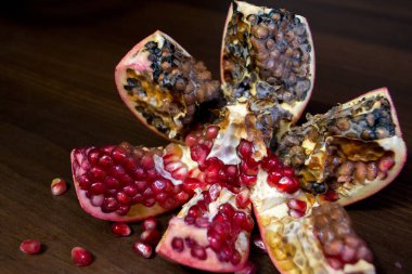 Çürük, şımarık, parlak kırmızı nar tohumları ile ahşap bir masa üzerinde.