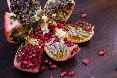 Çürük, şımarık, parlak kırmızı nar tohumları ile ahşap bir masa üzerinde.