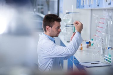 Başka bir soruşturma. Başka bir proje ile çalışıyor ve şişeyi elinde tutan laboratuvar oturan yetişkin perspektif güzel discoverer.