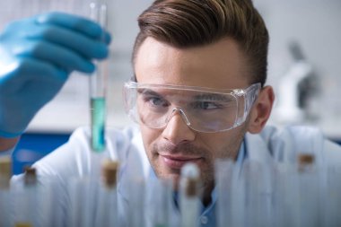 Başarılı araştırma. Genç hoş bilim gülümseyen ve o bakan şişe tutmak araştırma sonuçlarından memnun.