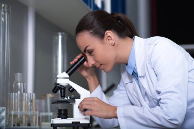 Microbiologists gerçeklik. Bir Tekdüzen ayakta laboratuarda mikroskop ile çalışma ve kapsamı içinde seyir yetişkin şirin makul bilim adamı.