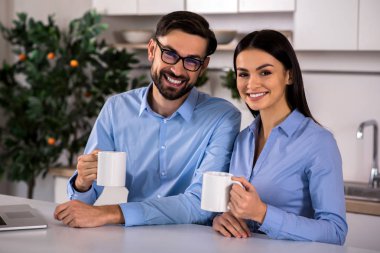 İçki ısınma. Neşeli genç çift çay içme sevgi dolu ve mutfakta oturmuş
