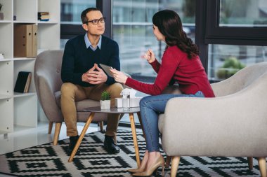 işadamı ve işkadını birlikte ofiste dijital tablet kullanırken konuşuyor