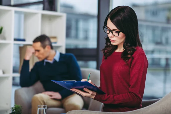 Vrouwelijke Psycholoog Maken Van Aantekeningen Het Document Klembord Met Boos — Stockfoto