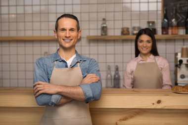 kafe sahibi çapraz kolları kafede garson arka planda ile ayakta olan portresi