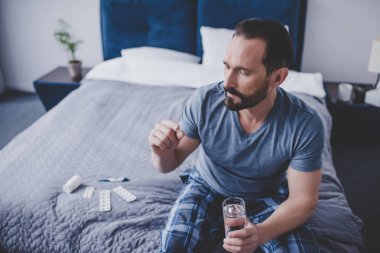 Beyaz adam hap ve yatağın üstüne oturan su tutan