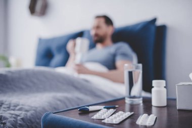 arka plan üzerinde çay içme yatakta hasta adam ile küçük tabloda hap yakın çekim