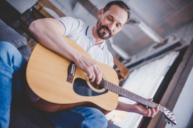 adam evde kanepede oturan gitar çalmak düşük açılı görünüş