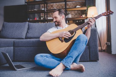 Beyaz adam evde katta oturan gitar çalmak
