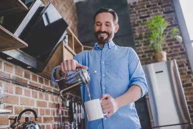 mutlu adamın kahve fincan içine sabah mutfakta dökme düşük açılı görünüş