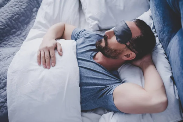 Portrait of handsome man in sleeping mask lying in bed