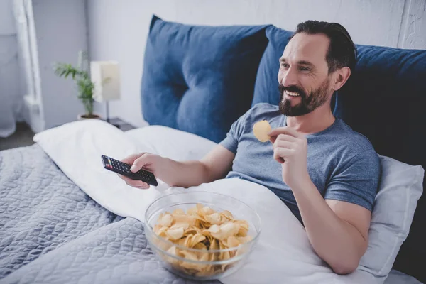 Retrato Del Hombre Sonriente Viendo Televisión Comiendo Patatas Fritas Mientras — Foto de Stock