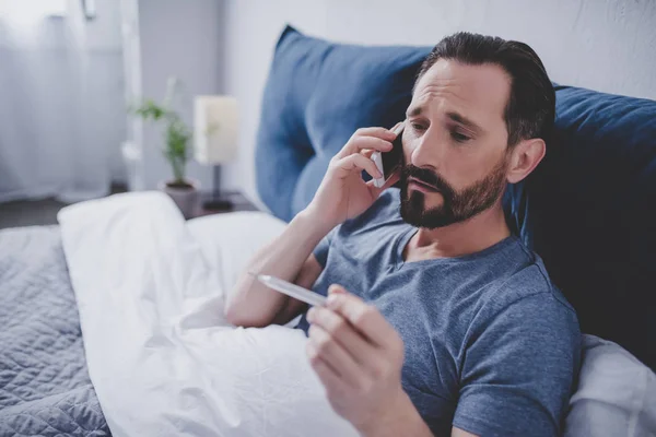 Retrato Del Hombre Enfermo Sosteniendo Termómetro Llamando Médico Mientras Está — Foto de Stock