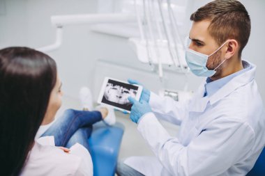 Doktor ve hasta x-ışını modern diş kliniği ile dijital tablet ekranına bakarak portresi