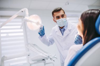Erkek diş hekimi modern diş kliniği kadın hasta dişlerini kontrol